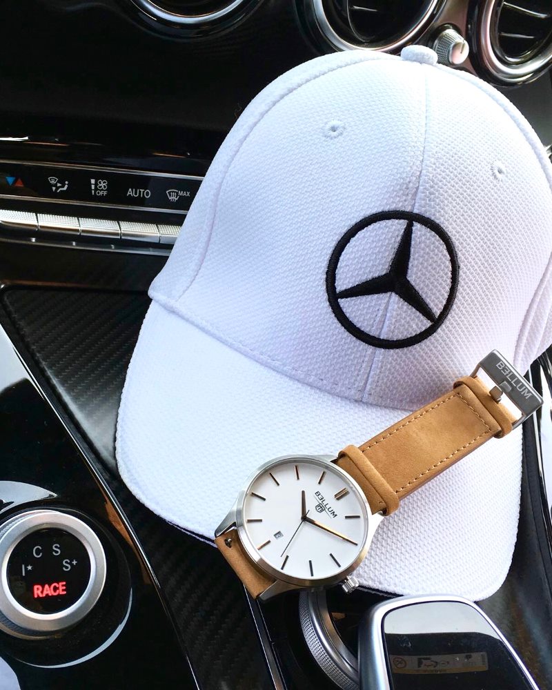 Reloj para hombre marca Bellum, color plata con dial blanco y correa de cuero camel. Imagen sobre gorra blanca en interior de Mercedes-Benz GTR.